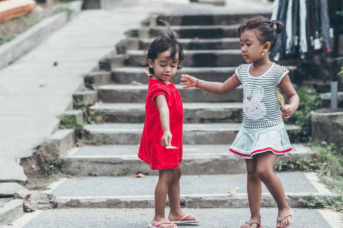 two toddler wearing red and gray dresses